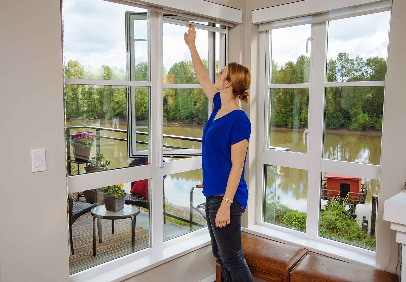 Woman pulling down a retractable fly screen on corner windows