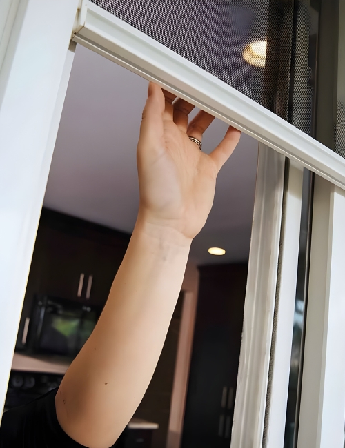 Hand pulling a roller fly screen down by its handle bar